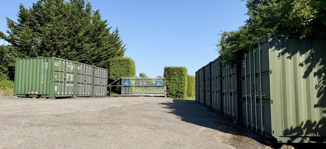 The gated entrance to Perry Storage seen from inside the yard, lined with containers